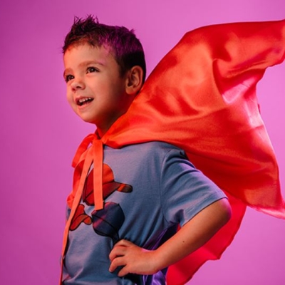 De afbeelding toont een jongetje met een superheldencape