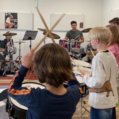 De afbeelding toont een klas kinderen die muziekinstrumenten bespelen