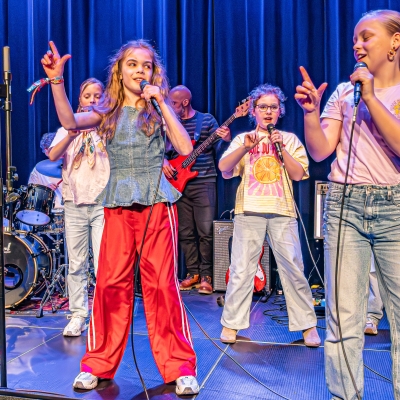 De afbeelding toont een groep kids die zingen/dansen/musical