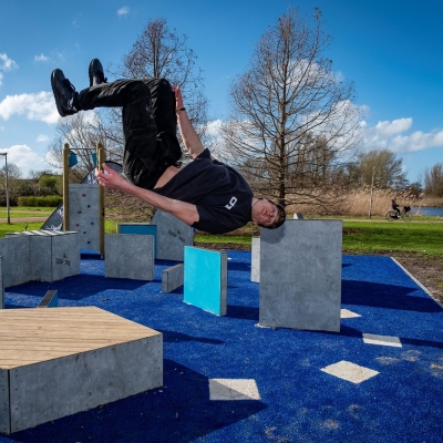 De afbeelding toont een jongen die aan het freerunnen is en een salto maakt
