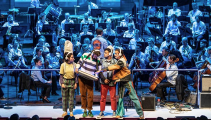 podium met optredende artiesten en orkest op achtergrond