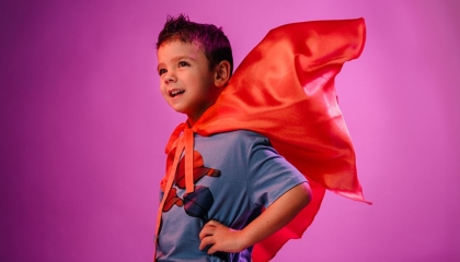 De afbeelding toont een jongetje met een superheldencape