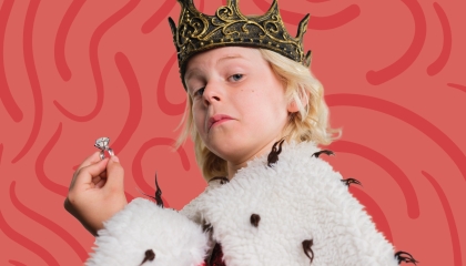 De afbeelding toont een jongetje verkleed als koning met een ring in zijn hand, een kroon op zijn hoofd, een bontjas om zijn schouders