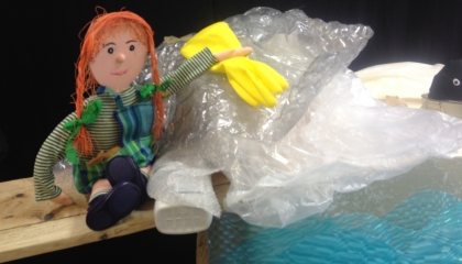 De afbeelding toont een pop (Wanda) tussen het plastic