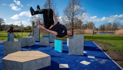 De afbeelding toont een jongen die aan het freerunnen is en een salto maakt